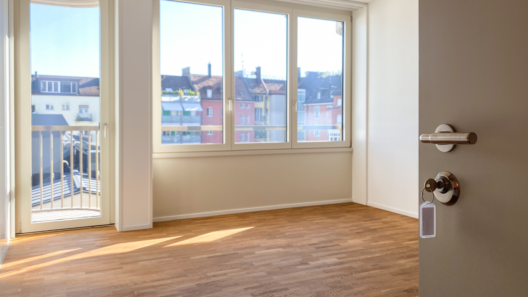 An empty room with a large window and a wooden floor