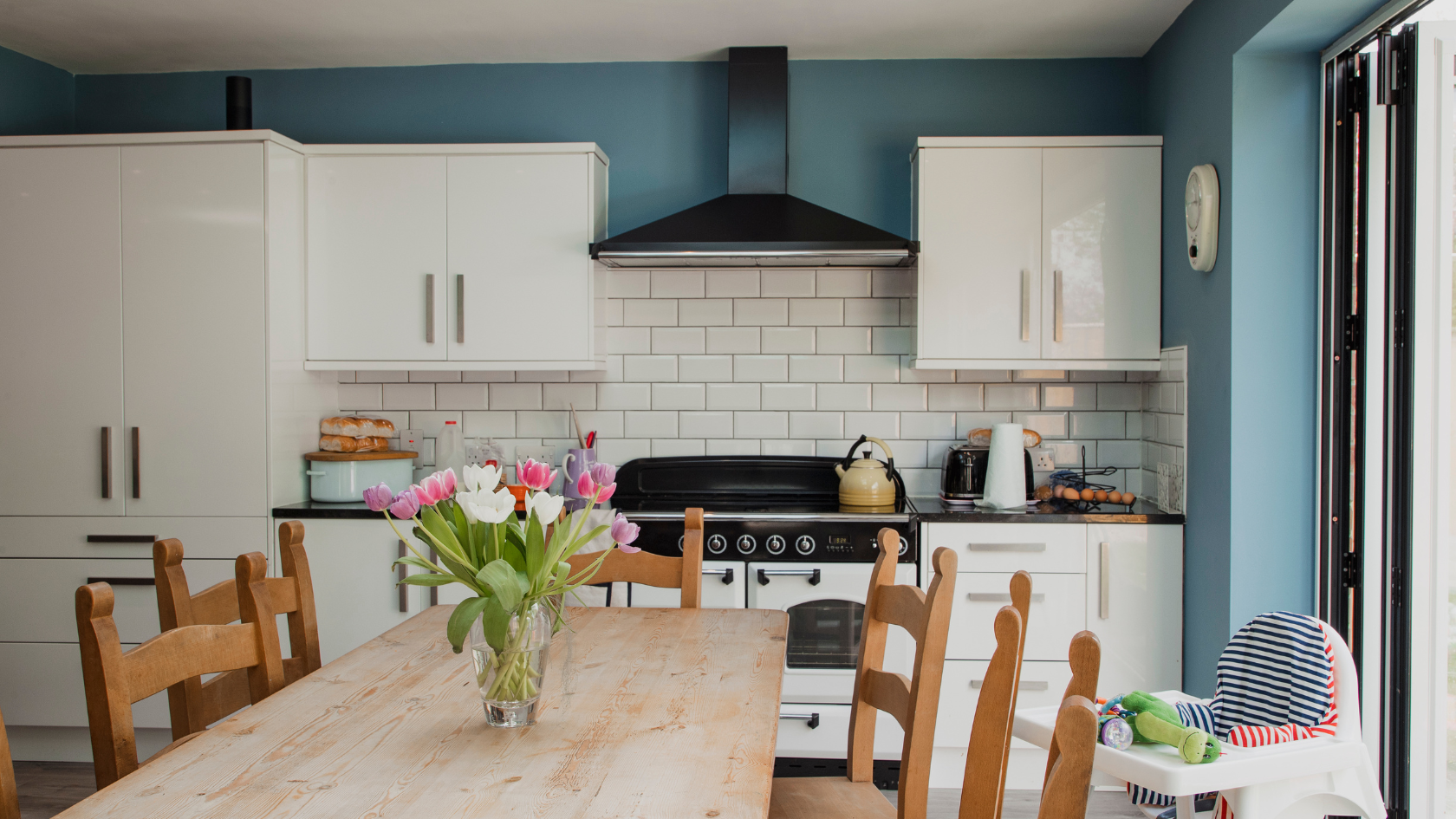 A kitchen with a table and chairs and a vase of flowers